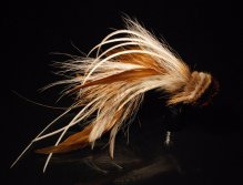 A combination of tan brown bucktail, brown schlappen feathers, white microbarb saddles with a tightly packed tan spun deerhair head