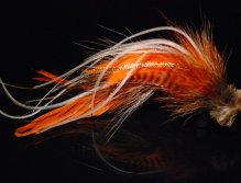 This is a combination of brown and orange schlappen mixed with tan bucktail and with microbarb saddles with a tightly packed tan deer hair head