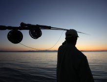 Mike McCoy, aka Dad, watches fish rise out of reach as the sun sets